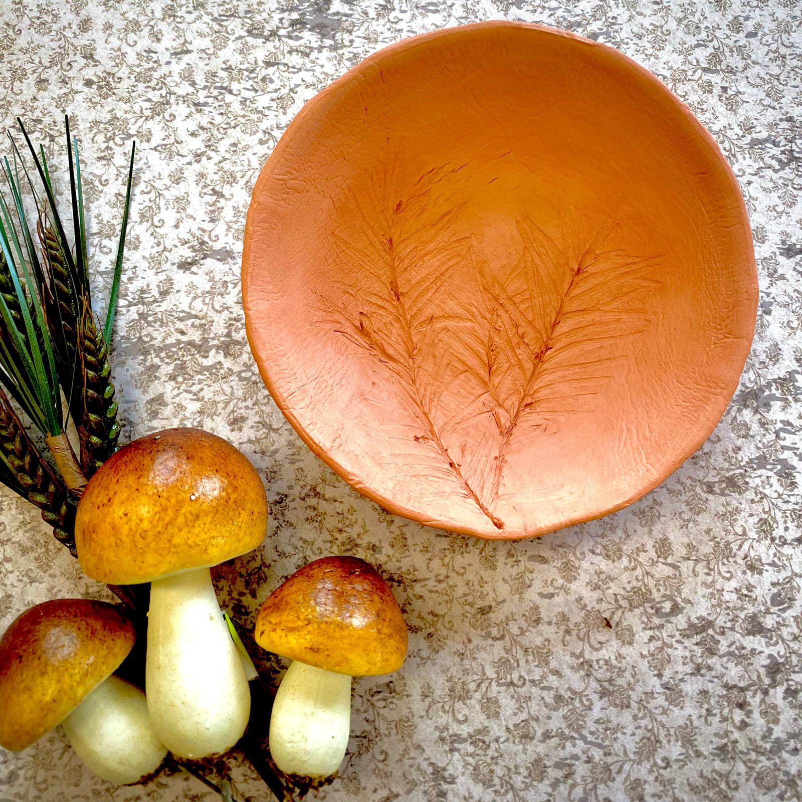 Ein Tonschälchen mit einer Verzierung und herbstliches Dekomaterial